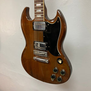 1975 Gibson SG Standard Walnut electric guitar with case, featuring a beveled mahogany body, visible tuning machines, and signature inlays.