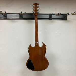 1975 Gibson SG Standard Walnut on a wall hook, close-up shows detailed fretboard and pickups.