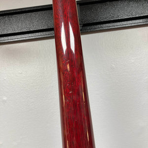 Close-up of the 1977 Gibson SG Standard Cherry by Gibson, its red glossy neck bearing visible scratches—set against a white wall and black horizontal rack, evoking the craftsmanship of the celebrated Kalamazoo era.