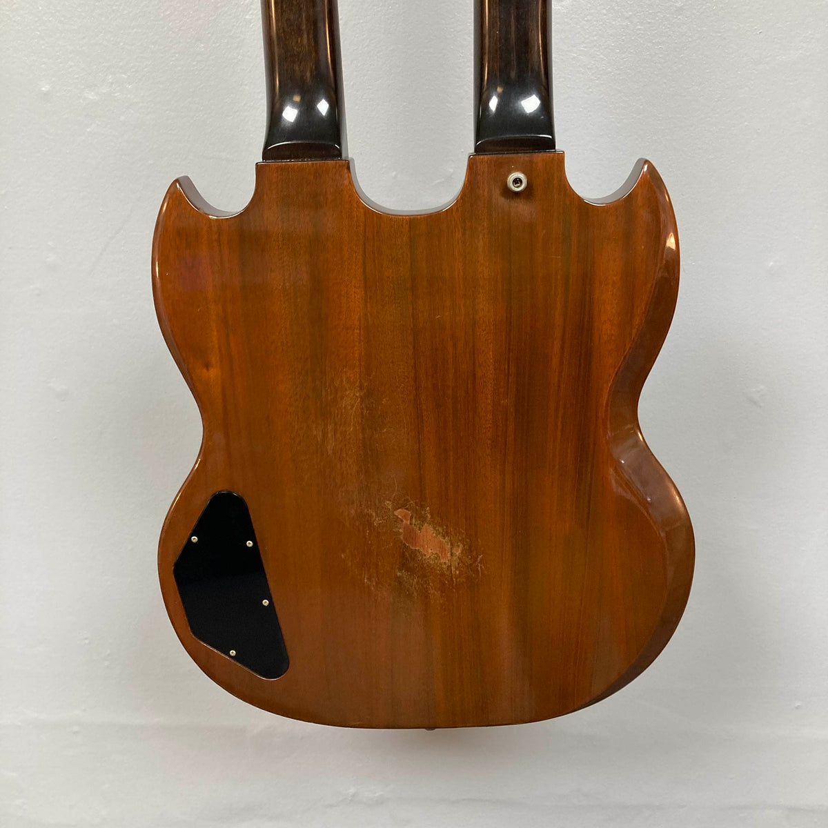 Rear view of a 1978 Gibson EDS-1275 Double Neck Walnut by Gibson, featuring a wooden walnut finish, visible signs of wear, and a black cover plate on the lower left side.