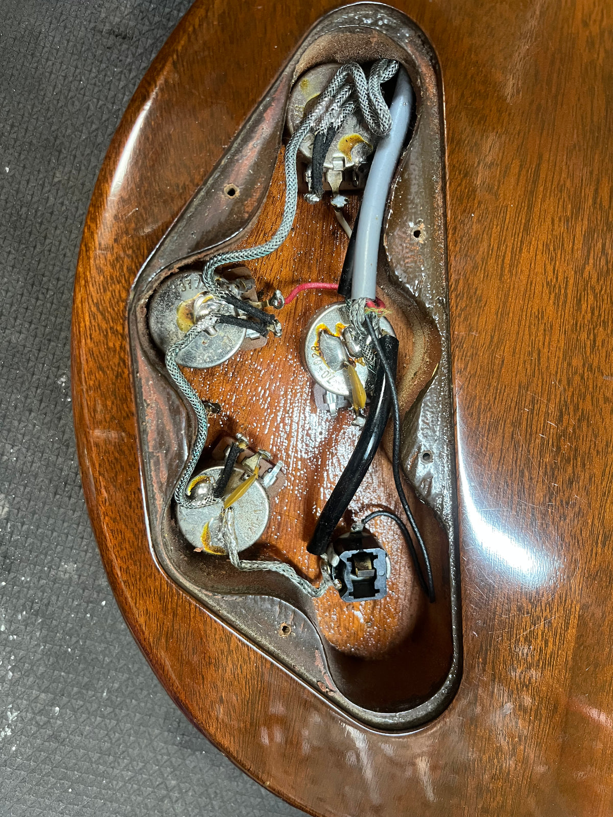 Close-up of a 1978 Gibson EDS-1275 Double Neck Walnut’s open control cavity, revealing its wiring, potentiometers, and jack on the rich brown body—an iconic Gibson design.