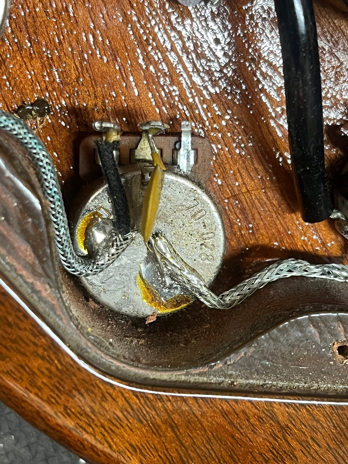Close-up of a potentiometer soldered to multiple wires, mounted on a wooden surface inside the electronics cavity of a 1978 Gibson EDS-1275 Double Neck Walnut w/Case by Gibson.