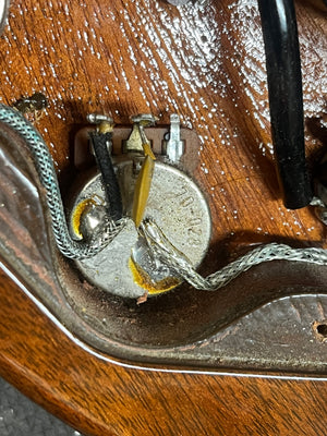 Close-up of a potentiometer soldered to multiple wires, mounted on a wooden surface inside the electronics cavity of a 1978 Gibson EDS-1275 Double Neck Walnut w/Case by Gibson.