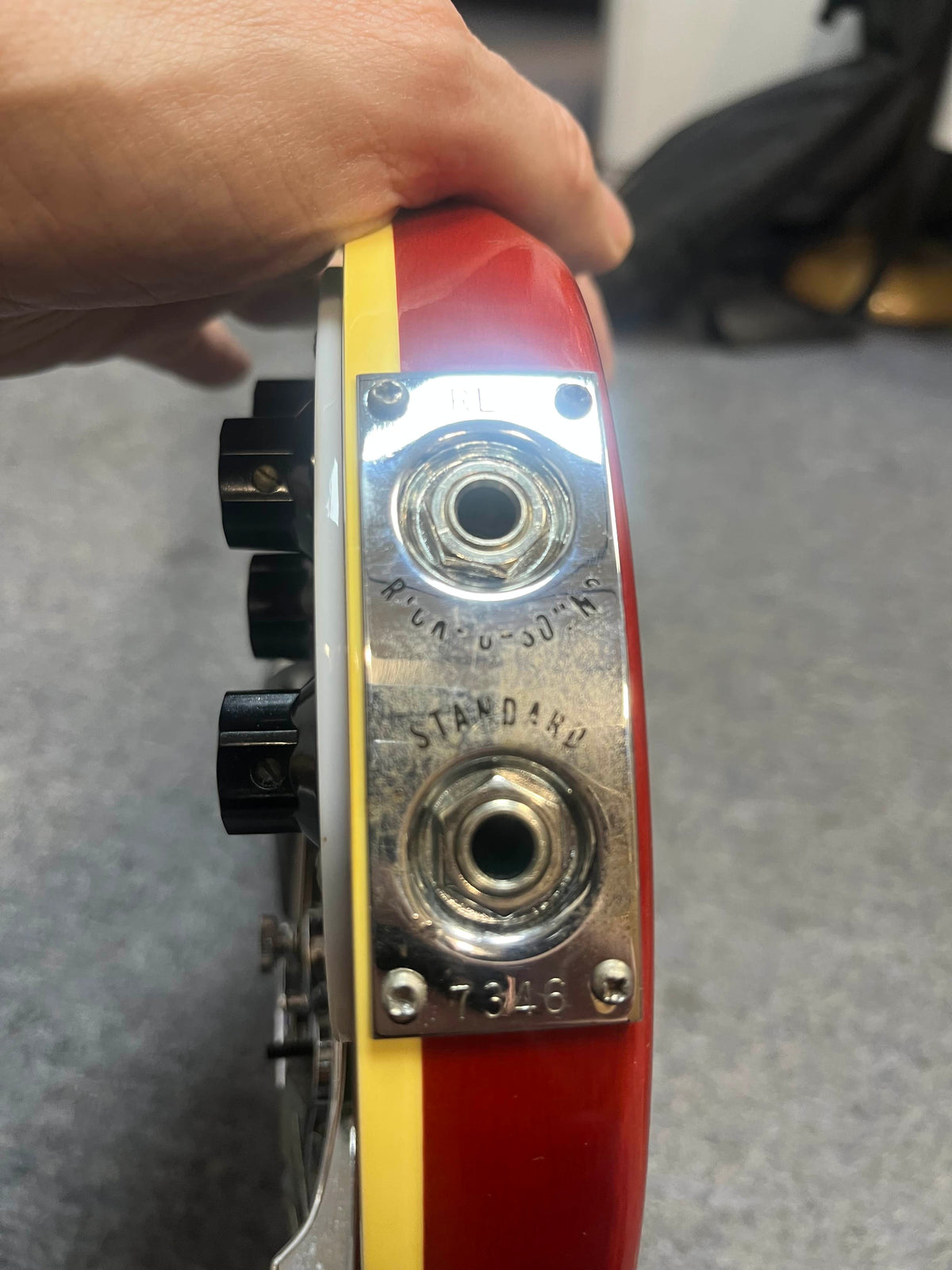 Close-up of a 1978 Rickenbacker 4001 Bass (Fireglo, Serial RL7346) input jack plate showing "RHYTHM/SOLO," "STANDARD," two jacks, and control knobs on the vintage Fireglo body.