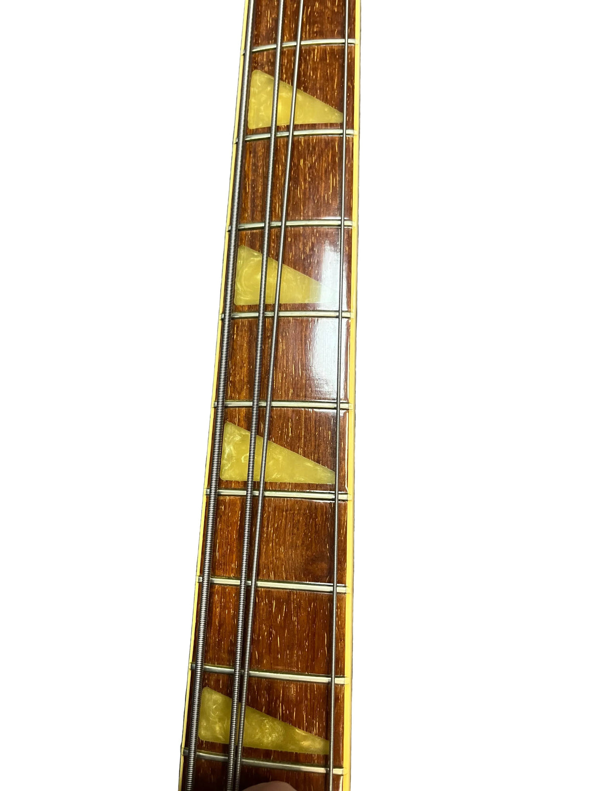 Close-up of a 1978 Rickenbacker 4001 Bass (Fireglo, Serial RL7346) neck with four metal strings, triangular yellow inlays, and rich wood grain—classic features of this vintage Rickenbacker, shown against a white background.