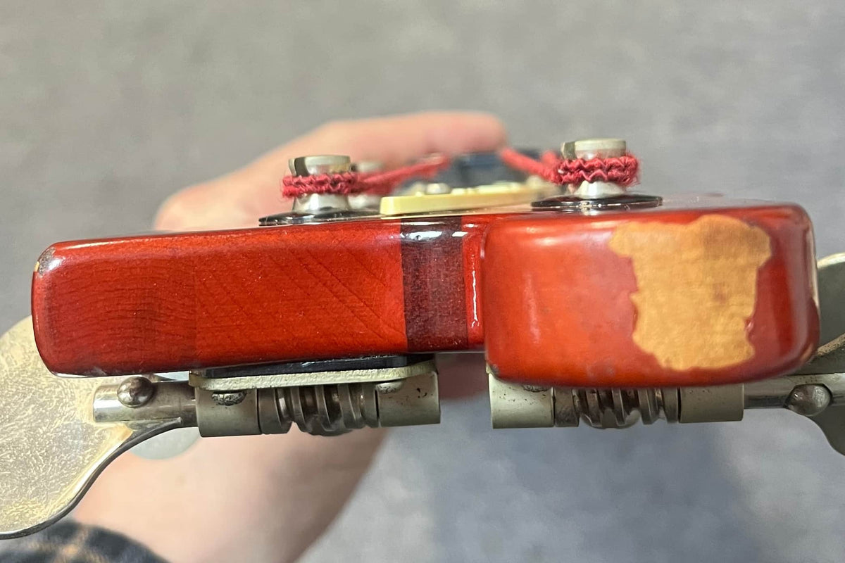 Close-up of the back of a 1978 Rickenbacker 4001 Bass in Fireglo (Serial RL7346) showing its worn finish and metal tuning pegs, held by hand.