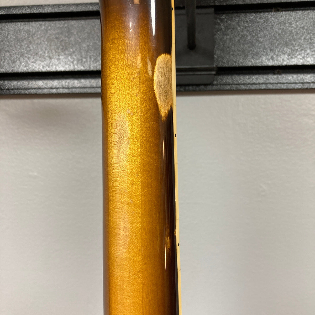 Close-up of the back of a 1980 Gibson Les Paul Custom – Tobacco Sunburst w/OHSC by Gibson, showing a worn patch on the neck where the finish has faded to reveal lighter wood beneath—classic vintage character.