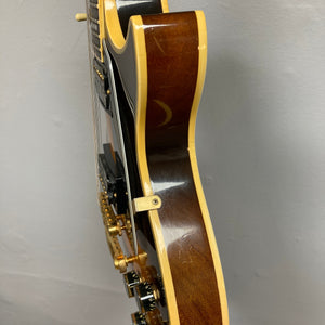 Side view of a 1980 Gibson Les Paul Custom – Tobacco Sunburst w/OHSC by Gibson, featuring cream binding and gold hardware, shown against a plain light wall.
