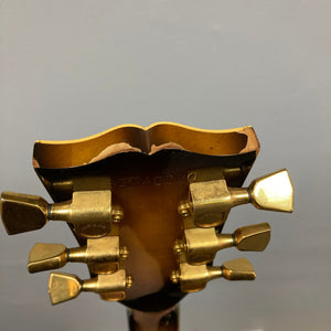 The back of this Gibson 1980 Les Paul Custom – Tobacco Sunburst w/OHSC displays gold tuners and wood wear along the top edge, showcasing a well-loved vintage guitar.