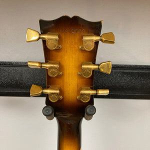 The back of a 1980 Gibson Les Paul Custom – Tobacco Sunburst shows six gold tuners, a serial number, and "Made in USA" above the neck, with the guitar on a stand.
