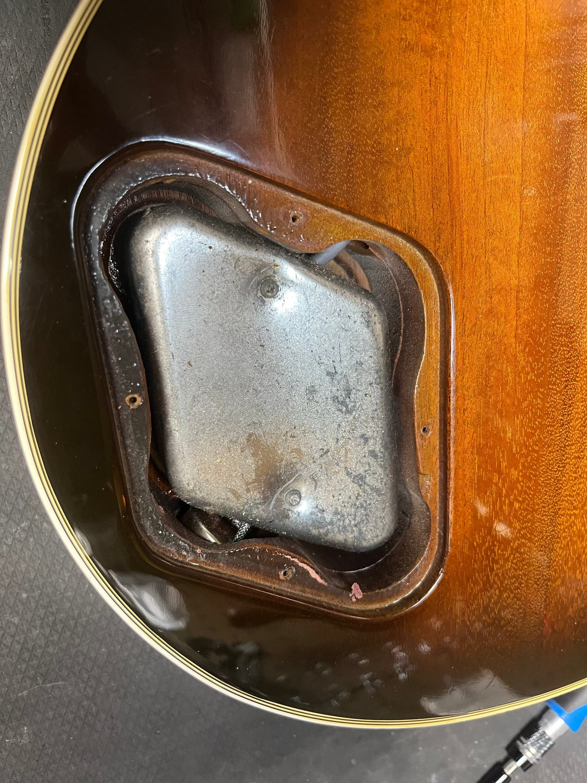 Close-up of the back of a 1980 Gibson Les Paul Custom – Tobacco Sunburst w/OHSC shows an open electronics cavity with its metal cover plate partially attached, highlighting this classic Gibson guitar’s vintage style.