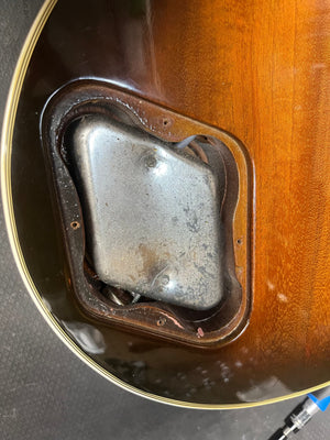 Close-up of the back of a 1980 Gibson Les Paul Custom – Tobacco Sunburst w/OHSC shows an open electronics cavity with its metal cover plate partially attached, highlighting this classic Gibson guitar’s vintage style.