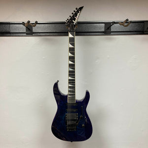 A 1995 Jackson SL1 Soloist Custom Shop Eerie Dess Swirl electric guitar by Jackson, featuring a pointed headstock and triangular inlays, is displayed on a wall-mounted guitar rack against a plain white wall.