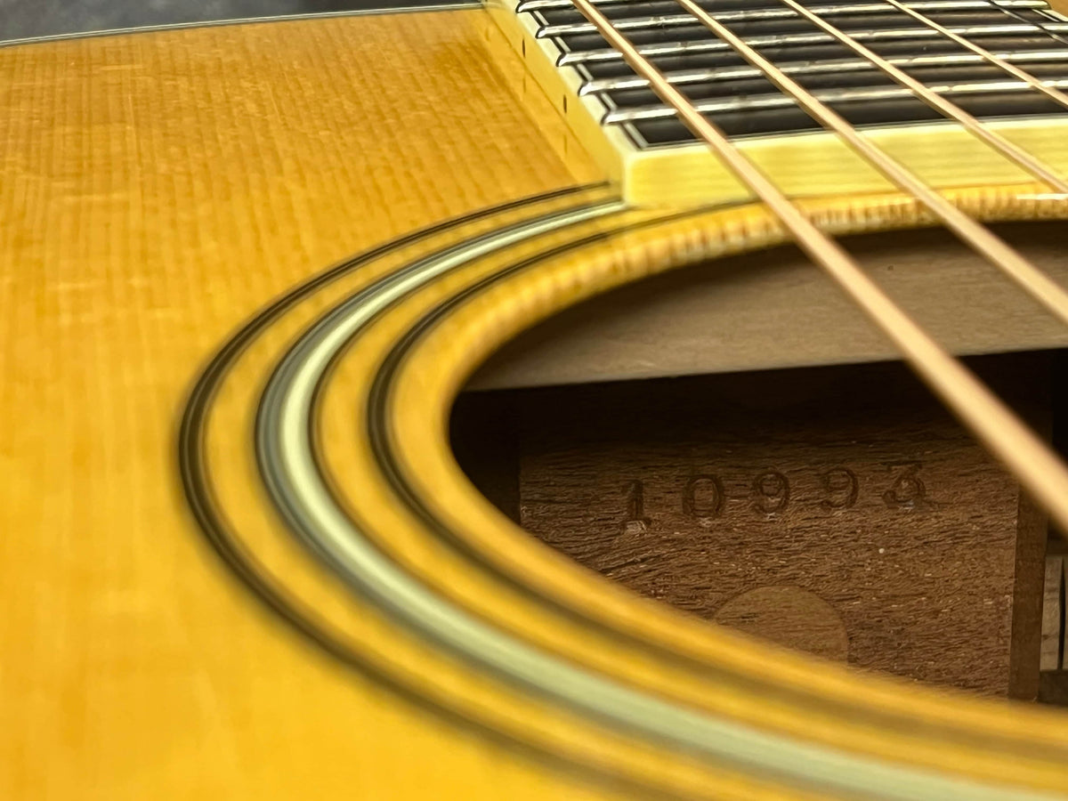 Close-up of a 2005 Collings CJ BaA acoustic guitar sound hole, showing fretboard, strings, and serial number "10993," highlighting its Brazilian rosewood back and sides with Adirondack spruce top.