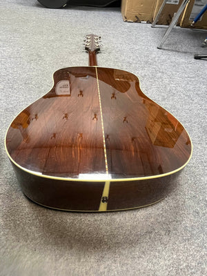 A close-up of the back of a 2005 Collings CJ BaA Brazilian Rosewood & Adirondack Spruce guitar, featuring a glossy wooden finish, resting on a gray carpeted floor.