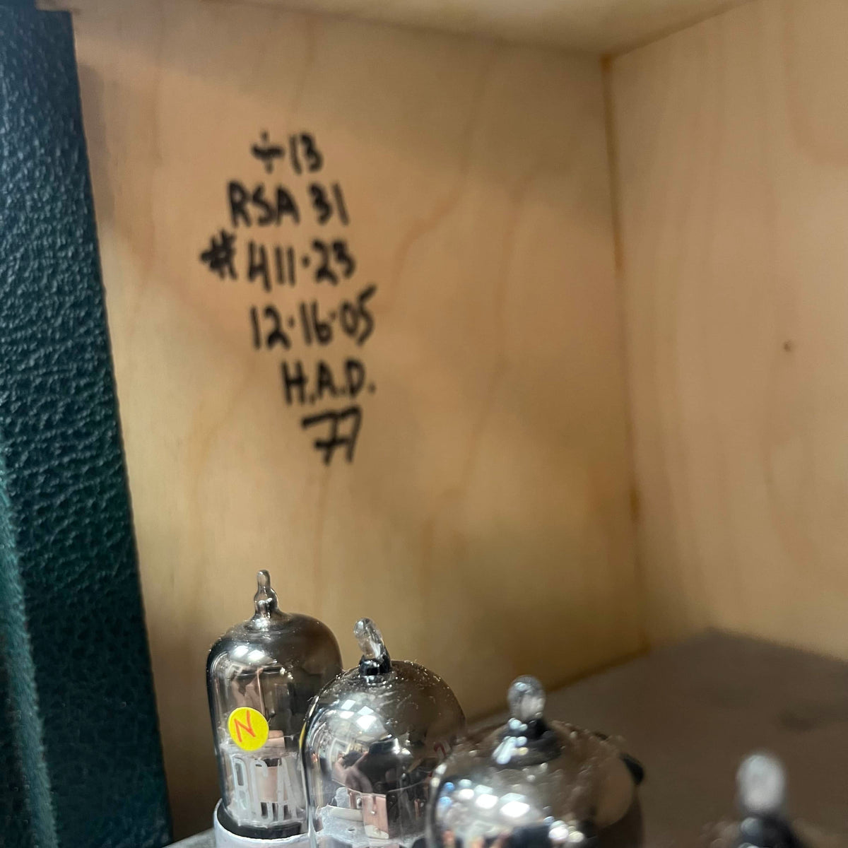 Vintage vacuum tubes with handwritten notes on a wooden surface