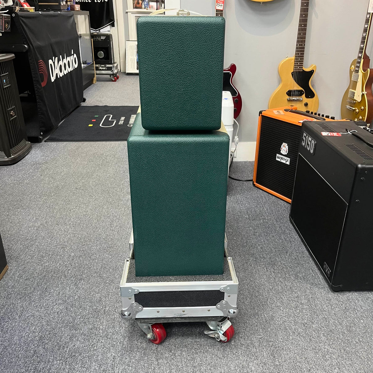 A 2005 Divided by 13 RSA 31 head with matching 2x12 cabinet and flight case is stacked on a rolling cart in a music store, surrounded by guitars and amplifiers. Local pickup for this Divided by 13 product is available.