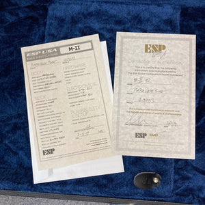 Two ESP specification and warranty cards, one of which features handwritten details, rest atop a blue velvet-lined surface—the perfect accompaniment to your American-made electric guitar, like the striking 2019 ESP USA M-II Purple Haze Burst w/Case from ESP.