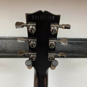 Back of a 2025 Gibson Les Paul Studio Modern in Smokehouse Satin, showing six tuning pegs and engraved serial "231550289"—a classic detail from Gibson. Includes Gator Molded Case.