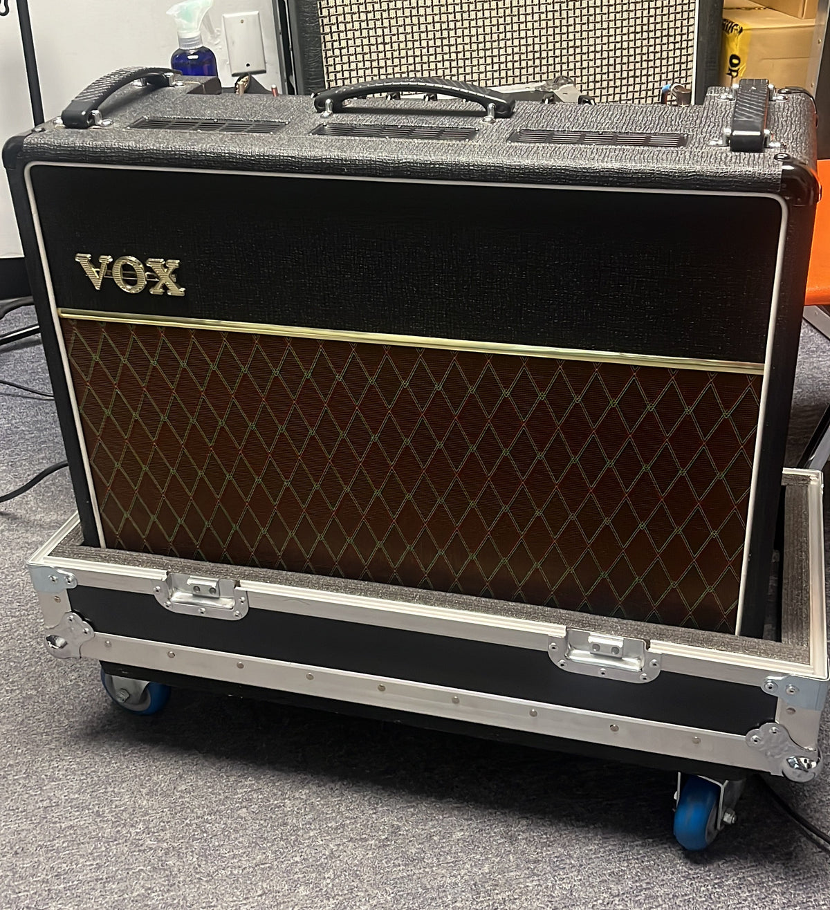 A 2004 Vox AC30/6TB guitar amplifier with Celestion Alnico Blues speakers sits on a wheeled metal case on a carpeted floor in a studio setting.