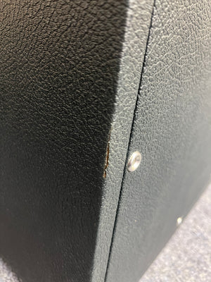Close-up of the black textured surface from a vintage 1969 Marshall 4x12 Cabinet with Matching Celestion T1281 Greenbacks, showing a small tear near the edge and two metal screws visible on the right side.