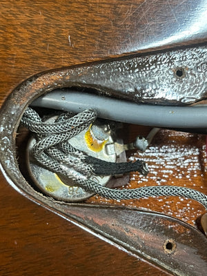 Close-up of the internal cavity of a Gibson 1978 EDS-1275 Double Neck Walnut w/Case, displaying wiring, a potentiometer, and braided cables set against the wood grain body.
