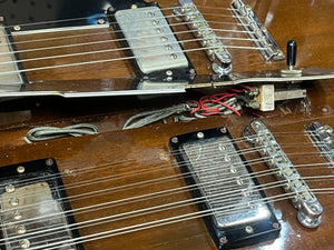 Close-up of a 1978 Gibson EDS-1275 Double Neck Walnut guitar by Gibson, showing exposed wiring and pickups, with a toggle switch visible near the upper set of strings.