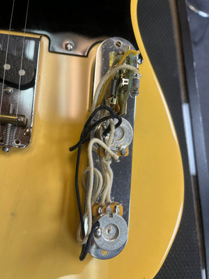 Close-up of a Fender Custom Shop '51 Reissue Nocaster NOS 2006 electric guitar in yellow, highlighting exposed wiring and control knobs with visible electronics on the control plate, reminiscent of a vintage blackguard model.