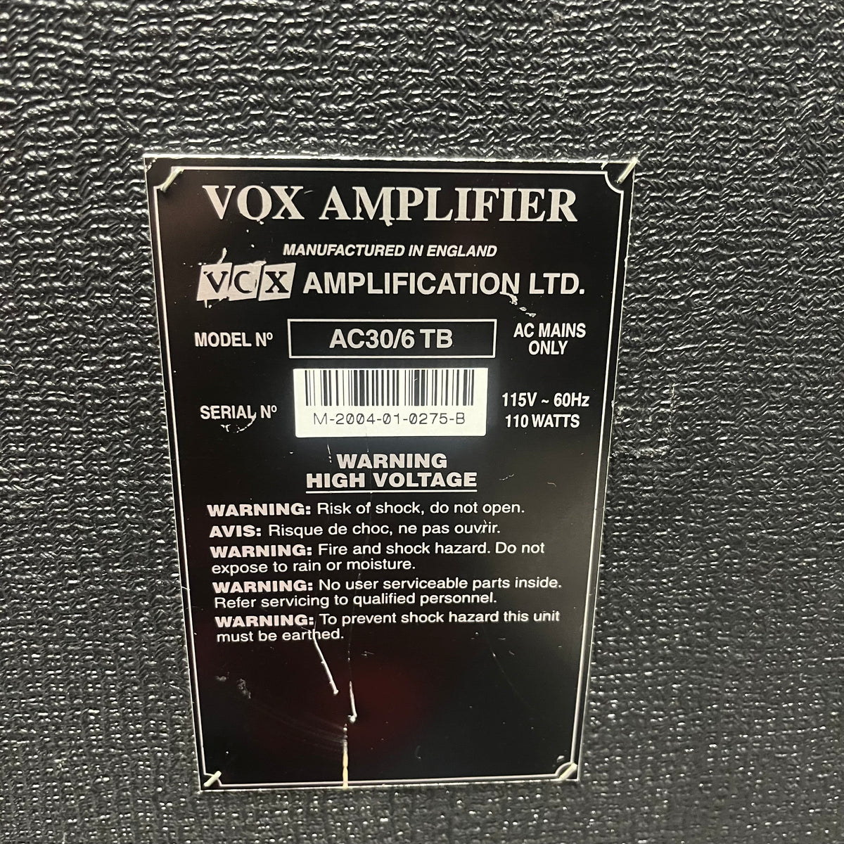 Close-up of a label on a 2004 Vox AC30/6TB amp, made in England with Celestion Alnico Blues speakers, showing model info, power ratings, serial number, and safety warnings.