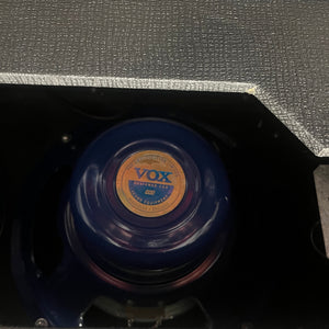 Close-up of a Vox AC30/6TB (2004, Made in England) Celestion Alnico Blues speaker inside a guitar amp housing, showing the label and part of the black textured covering.