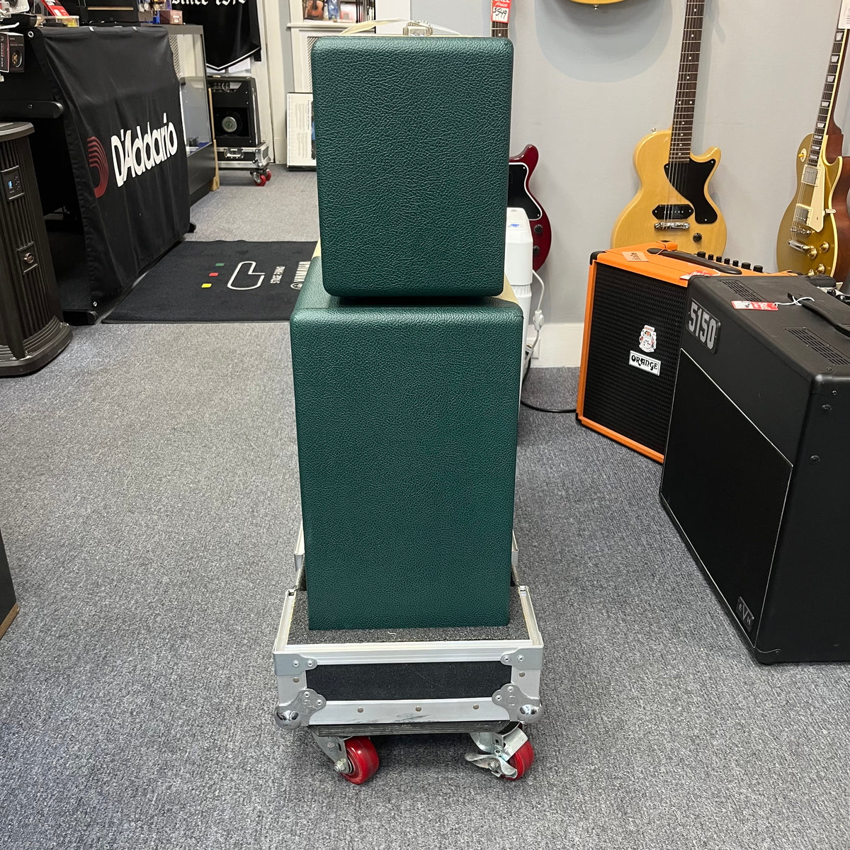 A 2005 Divided by 13 RSA 31 head with matching 2x12 cabinet and flight case is stacked on a rolling cart in a music store, surrounded by guitars and amplifiers. Local pickup for this Divided by 13 product is available.