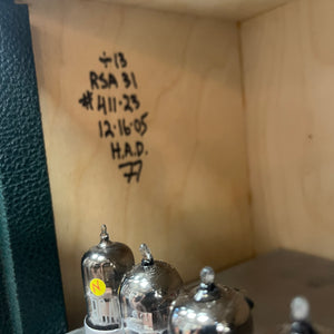 Vintage vacuum tubes with handwritten notes on a wooden surface