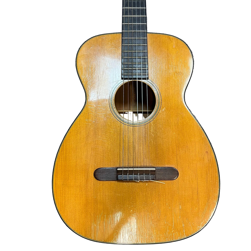 The Martin 00-18G Classical Guitar (c. 1961–1962) features a natural wood finish, six nylon strings, visible body wear, and a round sound hole—showcasing Martin’s timeless vintage charm.