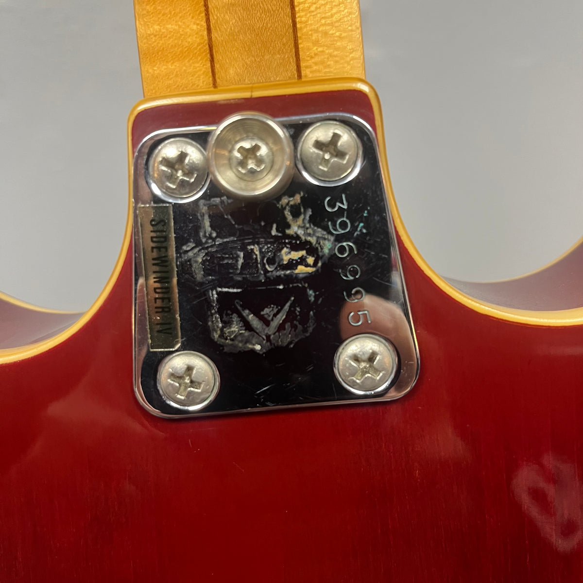Close-up of a Vox 1967-68 Sidewinder IV Bass (V272) Cherry neck plate with serial number 396995, four screws, and a partially worn "SUPERMODERN" sticker.