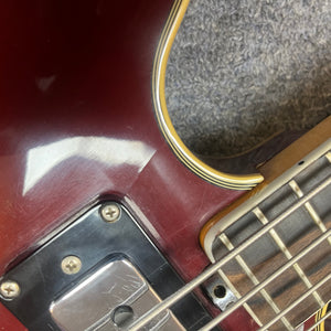 Close-up of a Vox 1967-68 Sidewinder IV Bass (V272) in Cherry, showing part of the semi-hollow body, metal pickup, strings, and fretboard on a carpeted surface.
