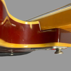 Close-up side view of the 1967-68 Vox Sidewinder IV Bass (V272) Cherry by Vox, focusing on the semi-hollow body and neck joint with strap button, finished in glossy red and yellow against a plain background.