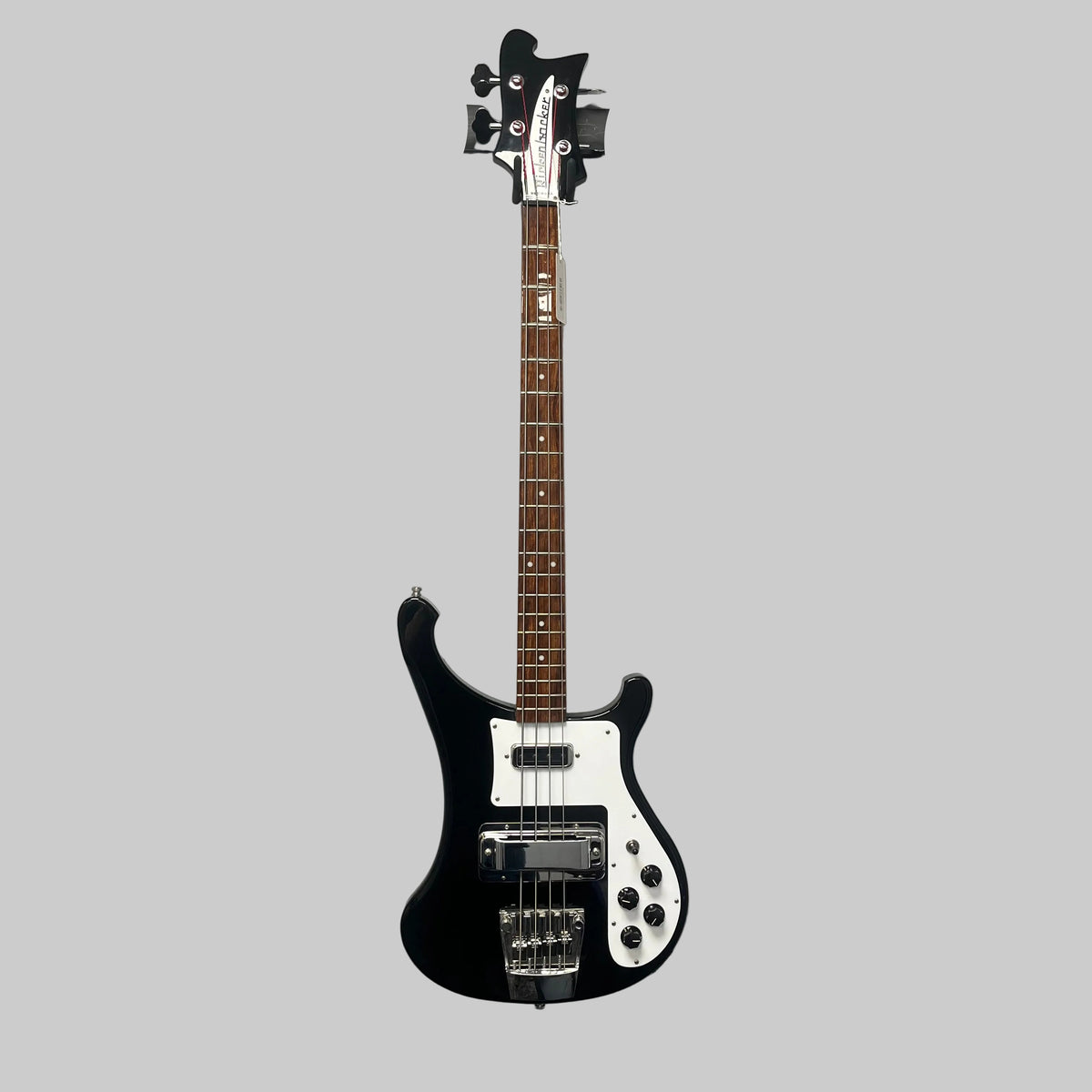 A Rickenbacker 4003 Bass Guitar – 2020 Jetglo w/Case and a red Fender Stratocaster electric guitar hang on a wall-mounted rack against a gray wall.