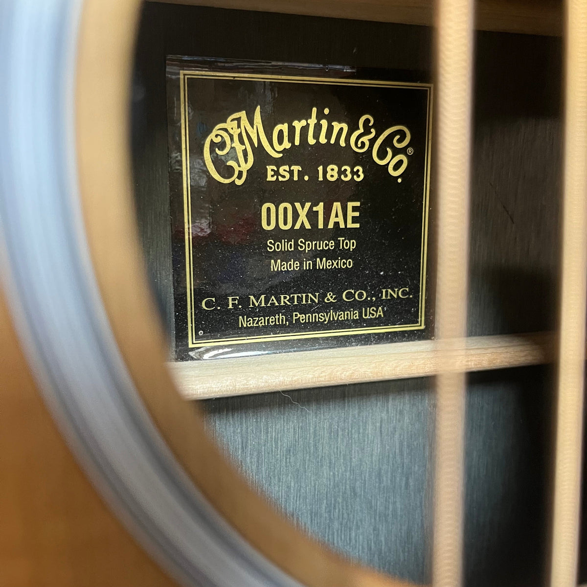 Interior view of a Martin 00X1AE Acoustic-Electric Guitar | Signed by Ex-Poison Guitarist Richie Kotzen soundhole showing a label with model specifications and an autograph.