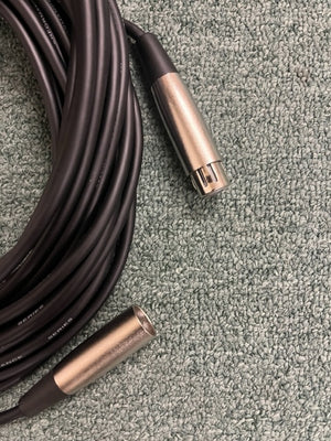 A coiled black American DJ MC-50 50ft XLR Microphone Cable with metal connectors lies on a textured gray carpet.