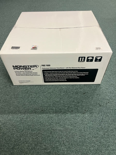 A sealed white box labeled "Monster Power PRO 7000 Professional Reference PowerSource" by Monster Power sits on a green carpeted floor, with handling symbols visible on the side.
