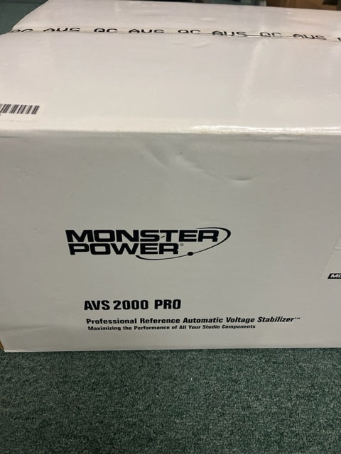 A white Monster Power AVS 2000 PRO Professional Reference Automatic Voltage Stabilizer rests on a green surface, making it an excellent choice as a professional studio power conditioner.