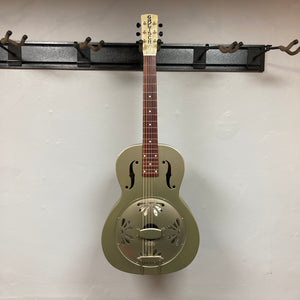 Gretsch G9201 Honey Dipper Round-Neck Resonator Guitar with brass body and distinctive resonator cone, displayed on a wall rack.