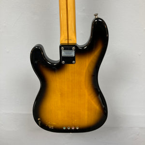 The back of a Fender Sting P Bass Sunburst is shown against a plain light wall, displaying its bolt-on neck, three string ferrules, and metal neck plate.