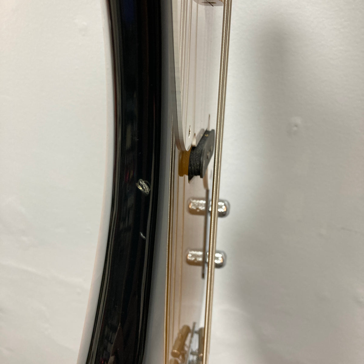 Close-up side view of a Fender Sting P Bass Sunburst neck and strings, with tuning pegs and part of the glossy sunburst body visible—a vintage-style electric bass from Fender against a white background.