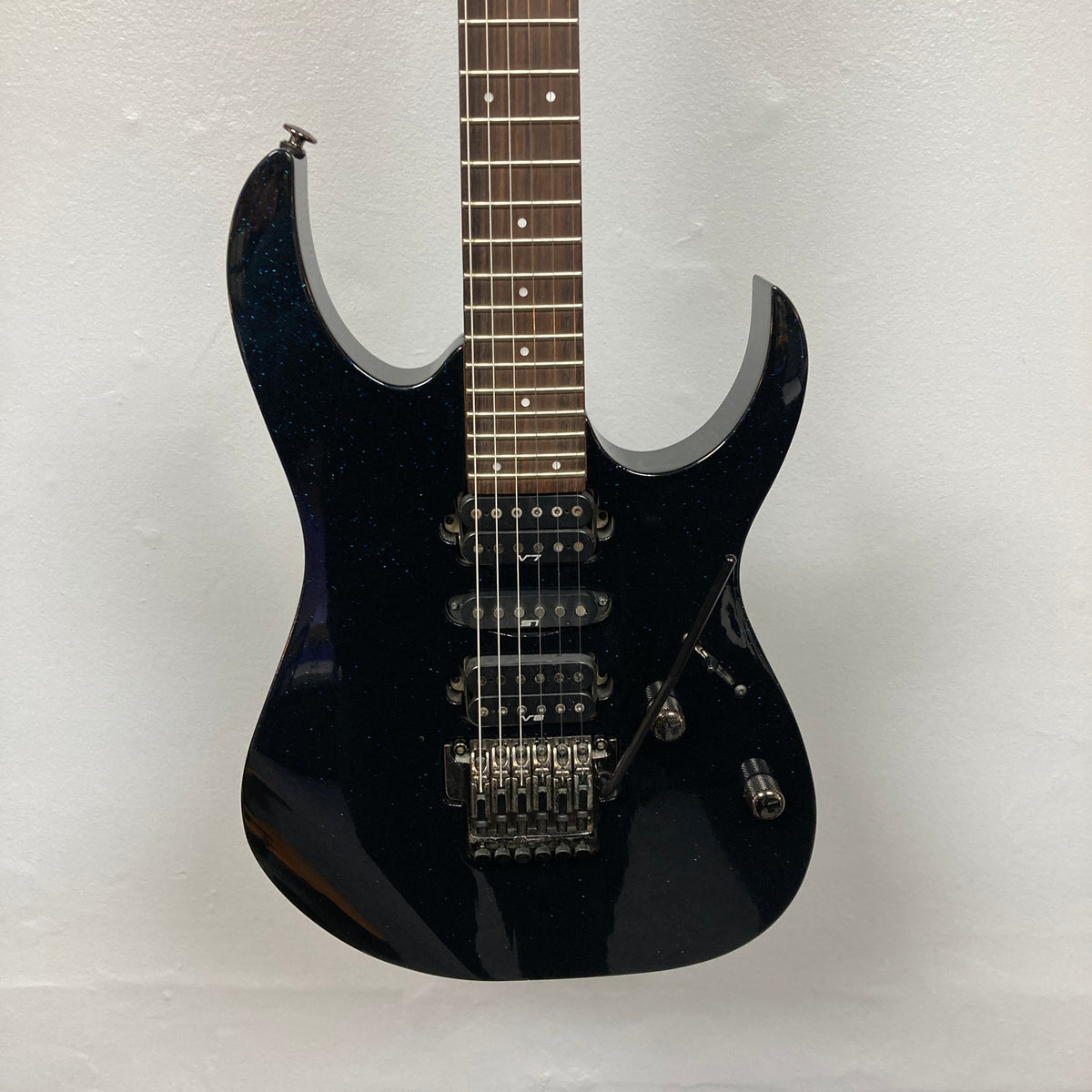An Ibanez Prestige RG1570 electric guitar in Cosmic Blue with a double cutaway body, three pickups, Wizard Prestige neck, tremolo bridge, and control knobs is shown with its case against a plain white background.