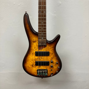 An Ibanez SDGR SR500PB 4-string bass guitar with a sunburst finish, flatwound strings, dual pickups, and multiple control knobs hangs on a plain white wall. Includes hard case.