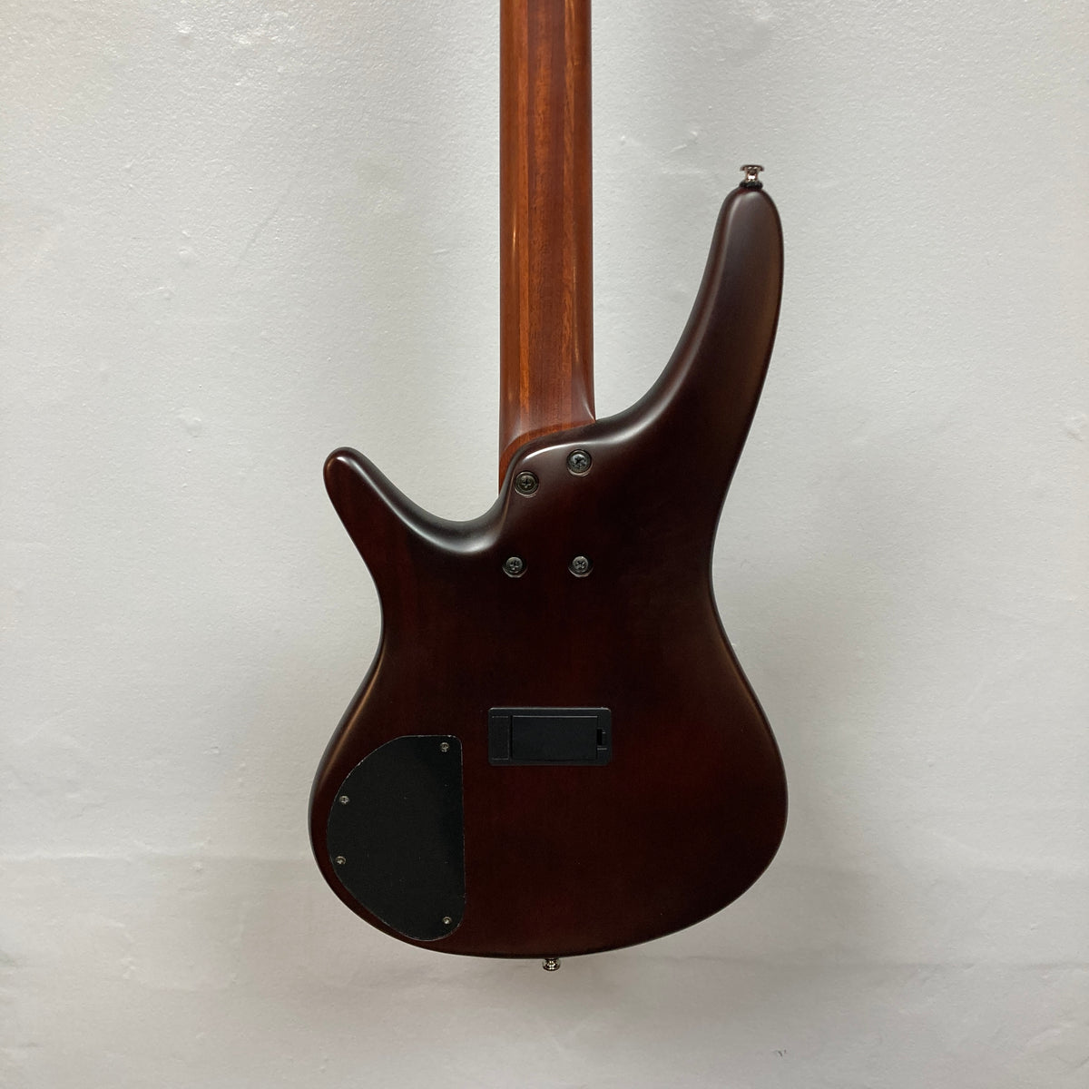 Back view of an Ibanez SDGR SR500PB w/Hard case bass guitar in dark brown, showing its smooth finish, visible neck, control cavity cover, and mounting screws against a plain light background.