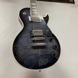 A used Schecter Solo-II Custom Trans Black Burst w/Case, featuring chrome hardware and four black knobs, USA Pasadena pickups, is displayed mounted on a white wall.