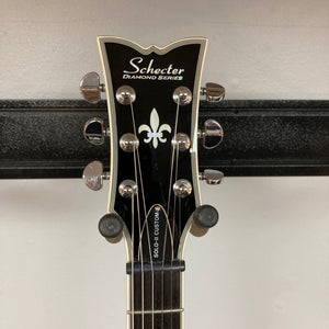 Close-up of a Schecter Solo-II Custom Trans Black Burst headstock with tuning pegs and fleur-de-lis inlay—featuring premium Schecter USA Pasadena pickups.