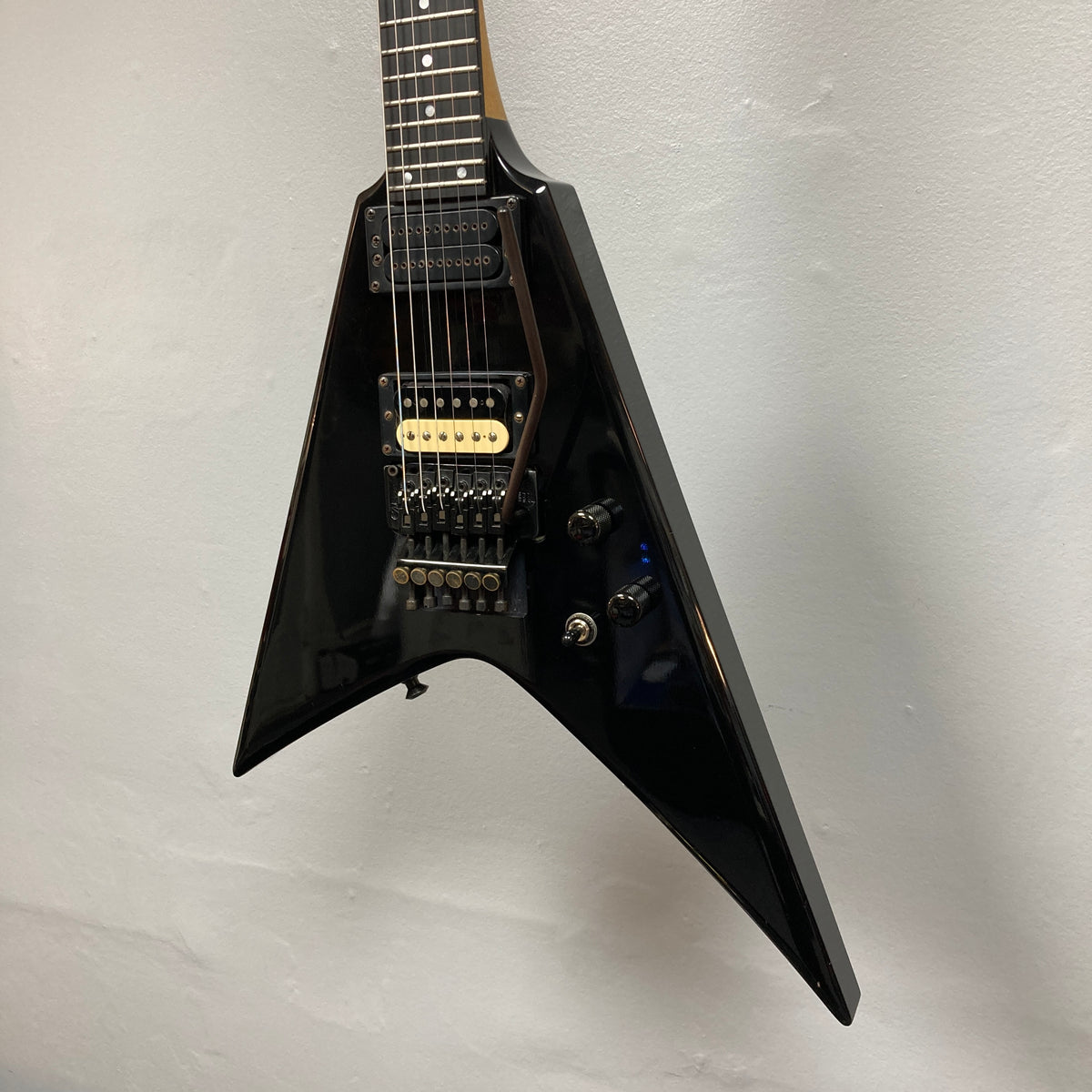 A black 1992 Carvin Ultra V USA electric guitar with a Kahler Steeler Trem, MJ-wound Seymour Duncan DCJ humbuckers, and multiple control knobs hangs against a light-colored wall.